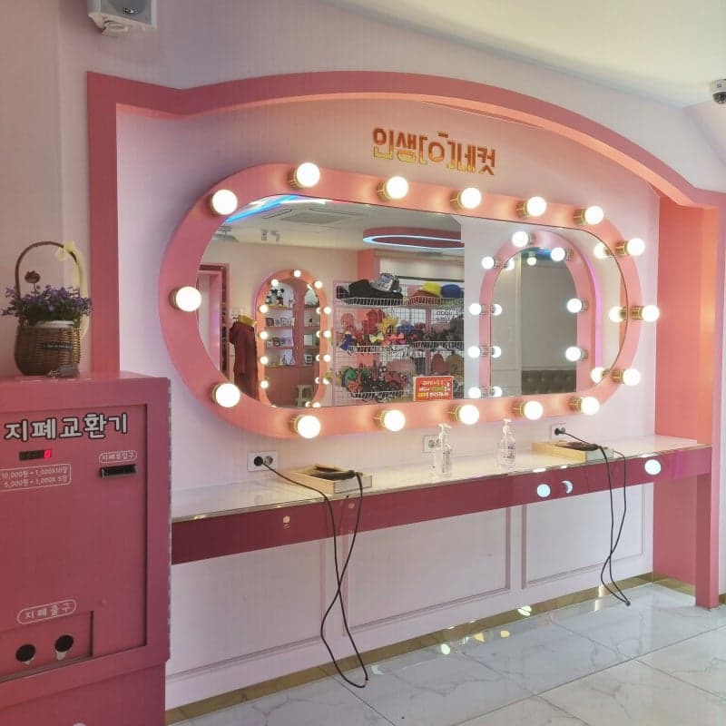 Pink vanity mirror wall with lightbulbs inside a Life4Cuts photo studio in Korea