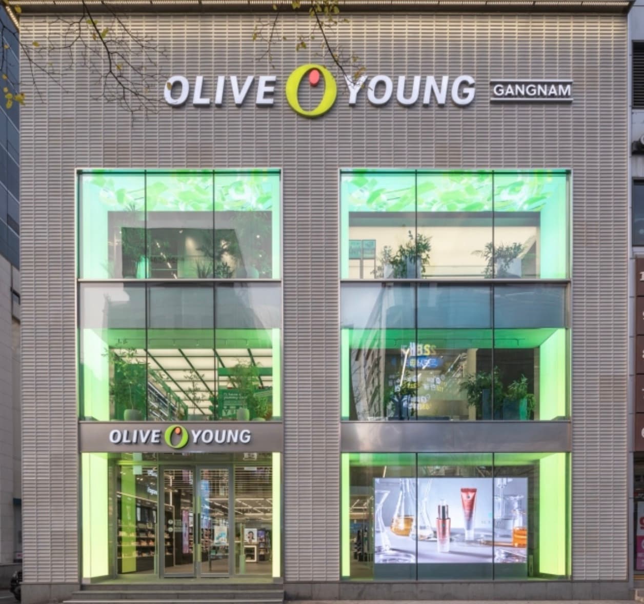 Exterior of the Olive Young Gangnam flagship store with green-lit glass facade